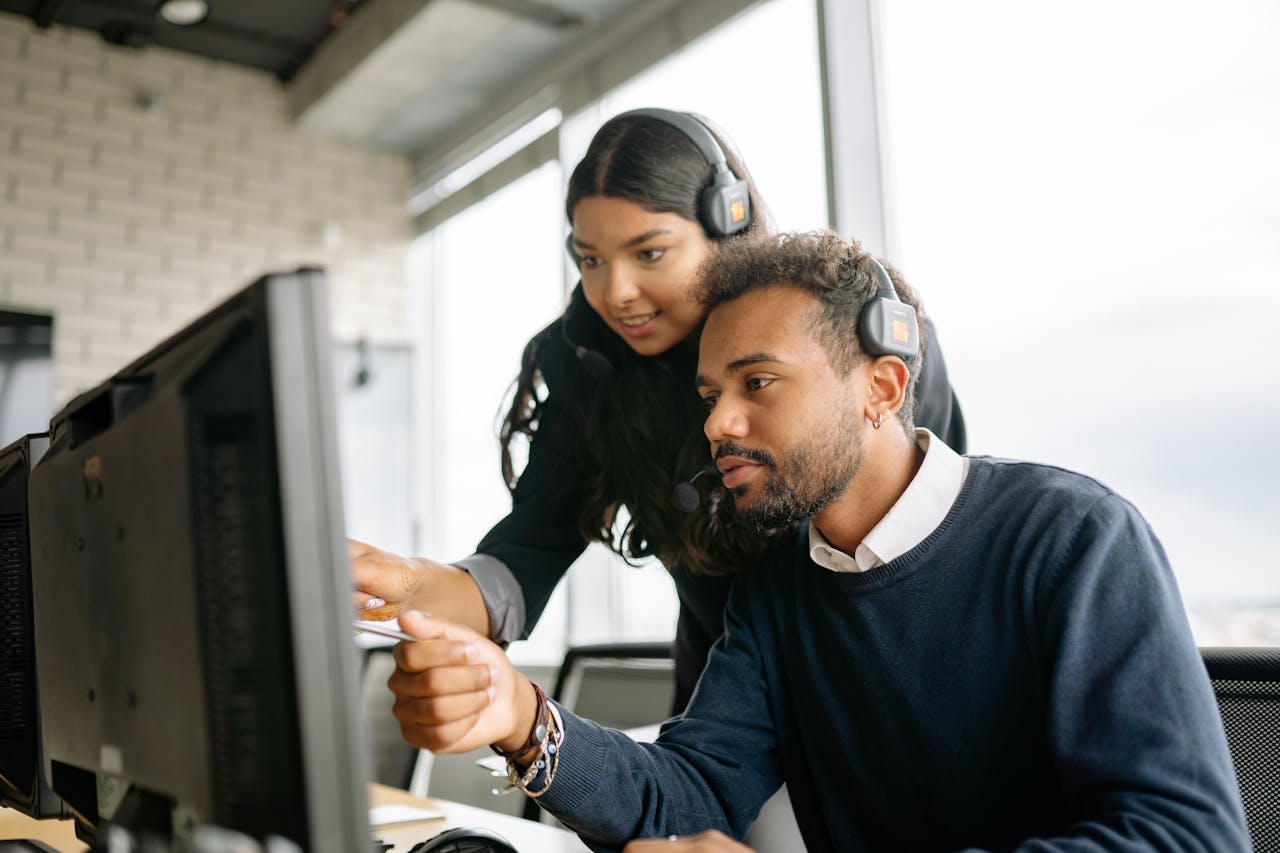 about-02 Two call center employees working together with headsets in a modern office setting.